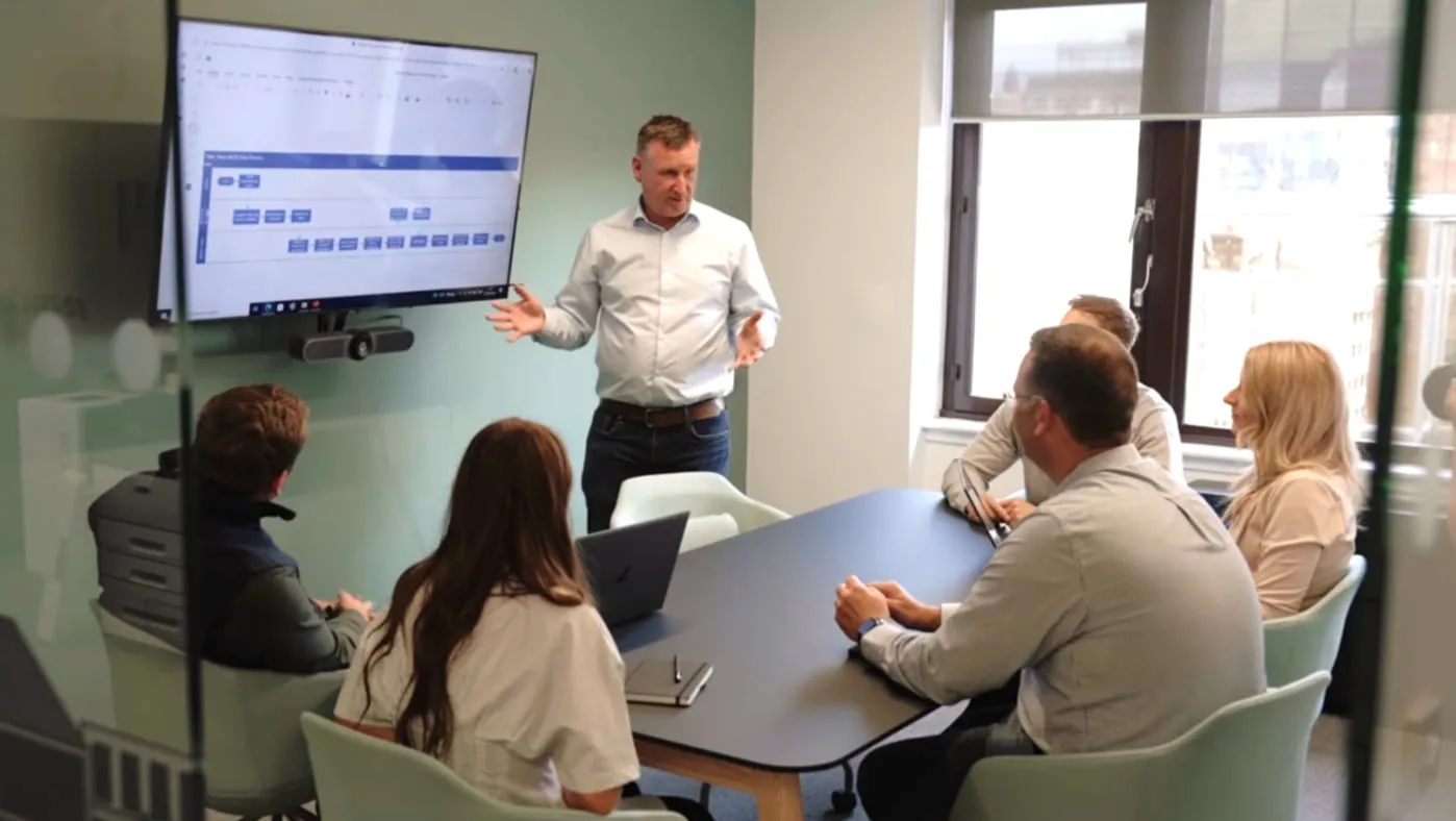 A consultant presents to a client team seated around a meeting table